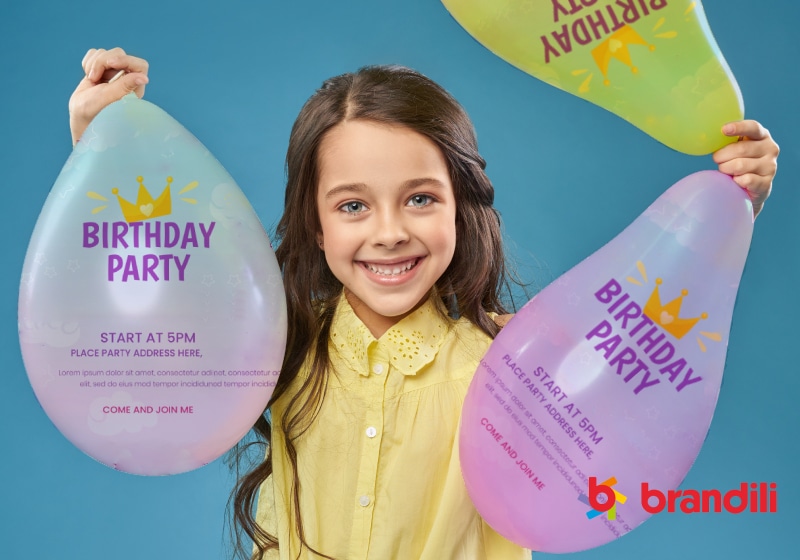 menina sorridente segurando três balões com convite de aniversario escrito neles 