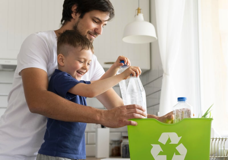 Pai e filho guardando garrafas plásticas para reciclagem