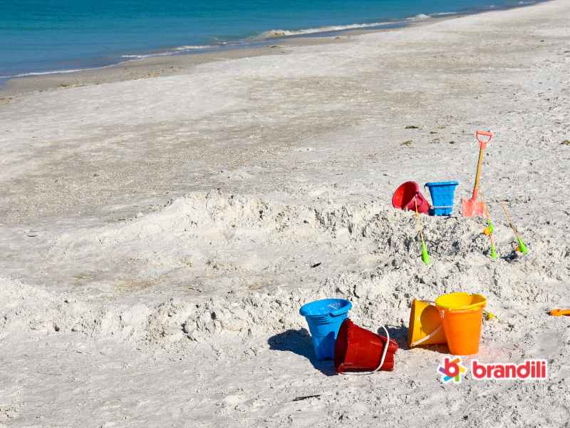 baldes e brinquedos colocados sobre a areia da praia