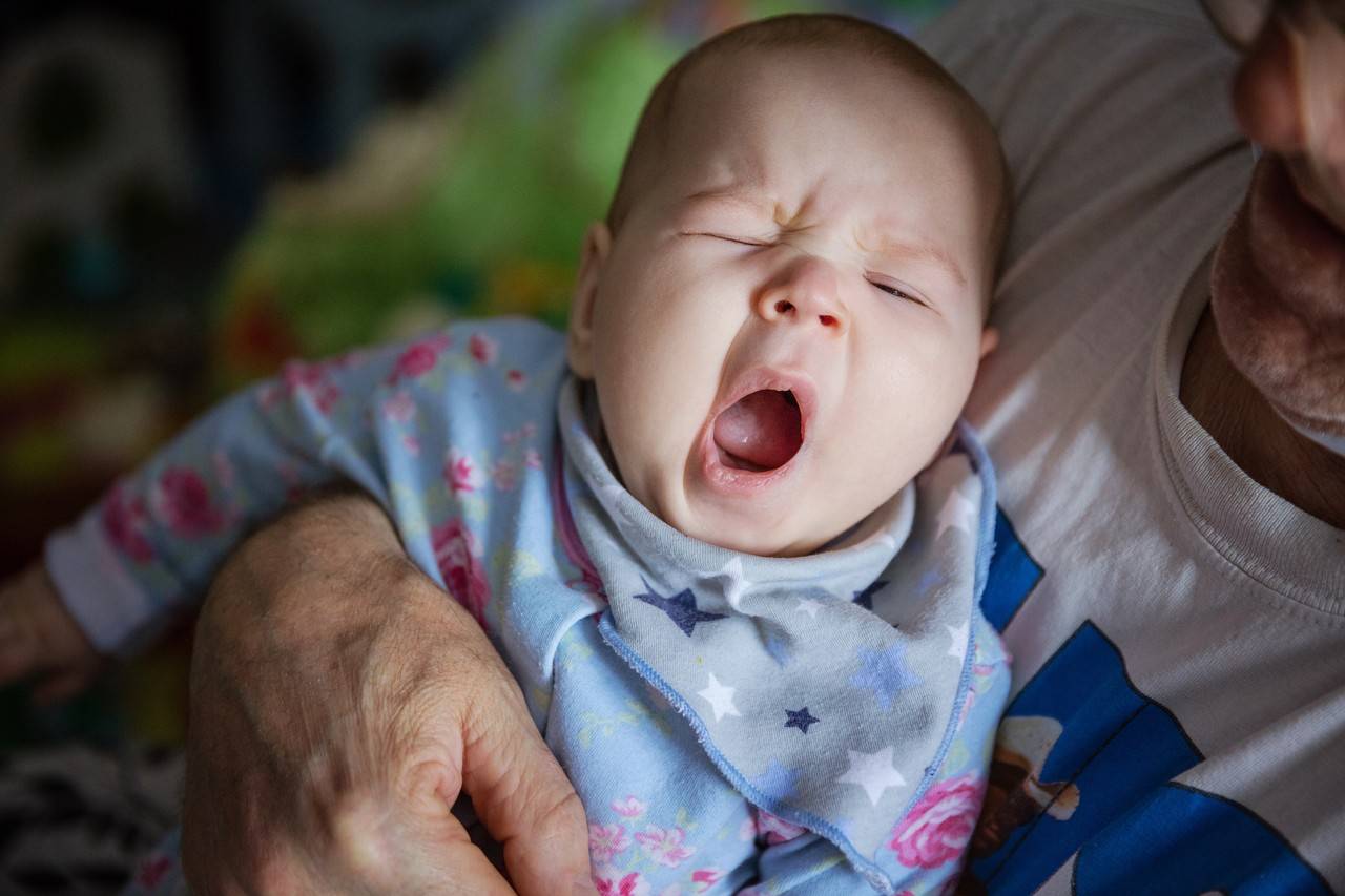 bebê boquejando de sono no colo do pai