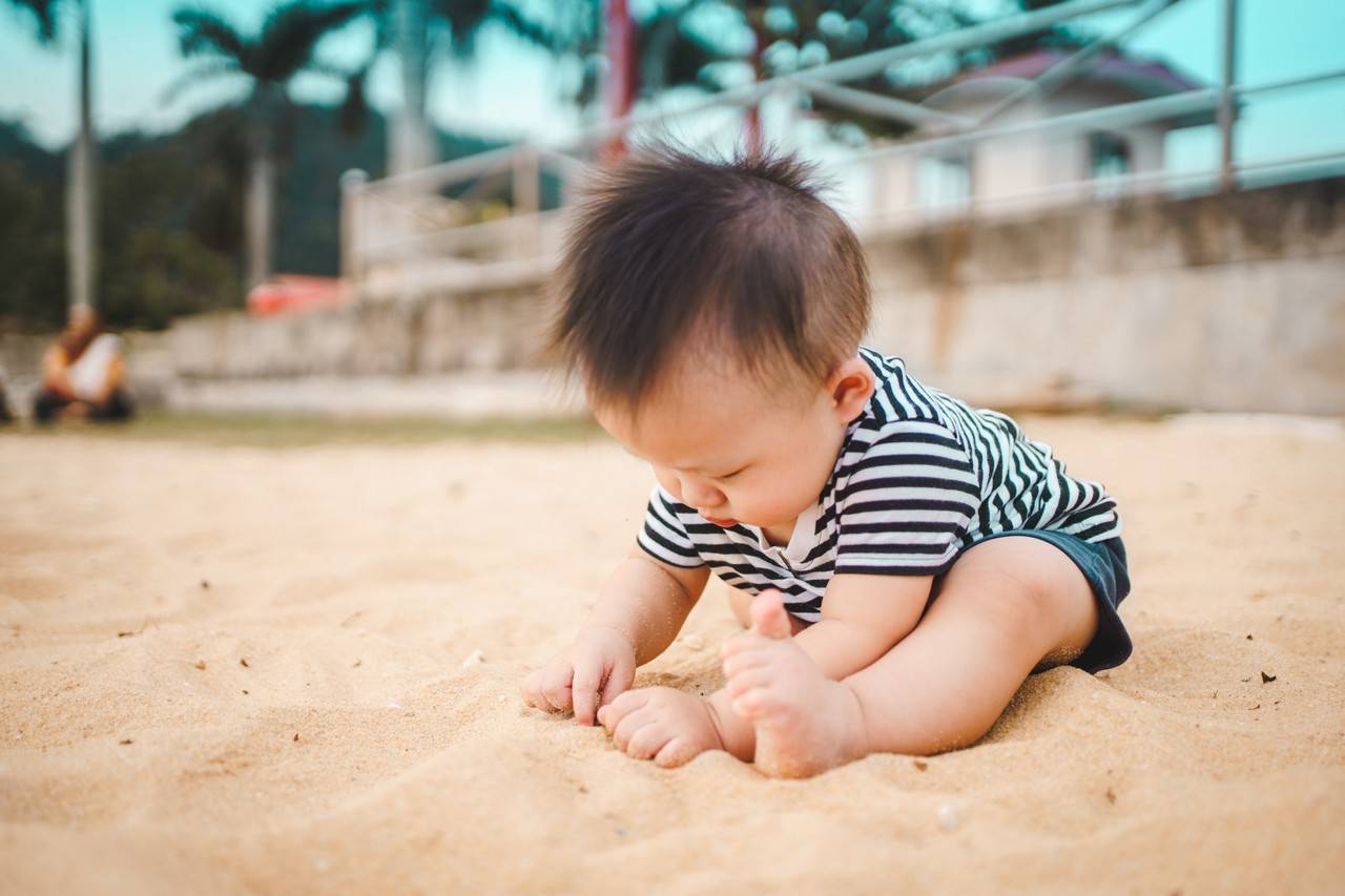 bebê se divertindo na areia durante o verão