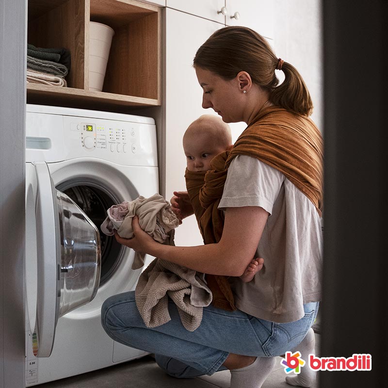 mãe-com-seu-filho-abaixados-colocando-roupa-na-máquina-de-lavar