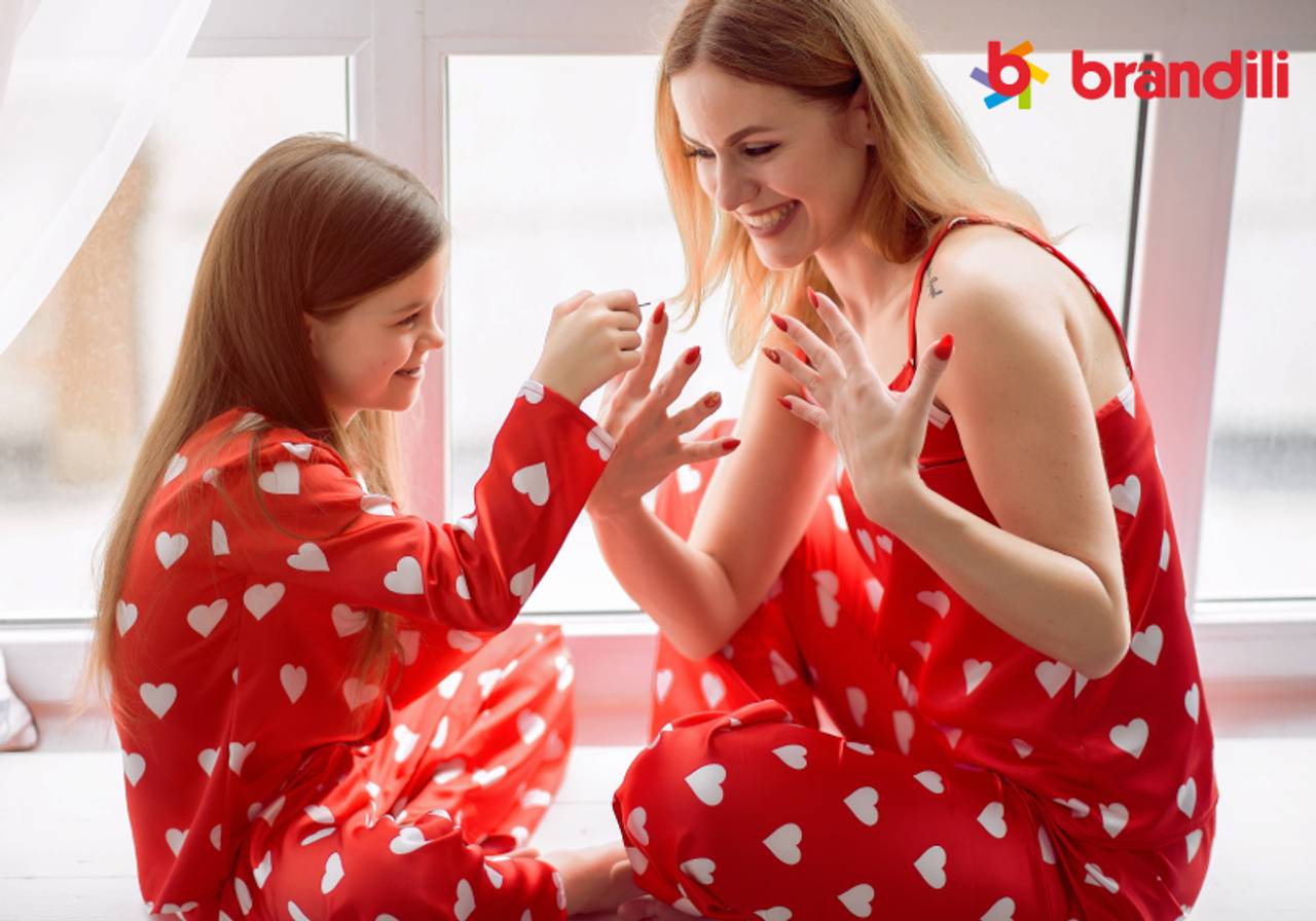 mãe e filha com pijamas iguais de coração e filha fazendo a unha da mãe