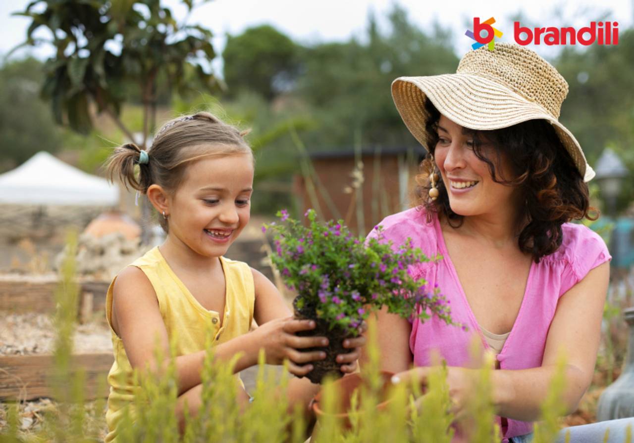 mãe e filha plantando muda de flor no vaso 