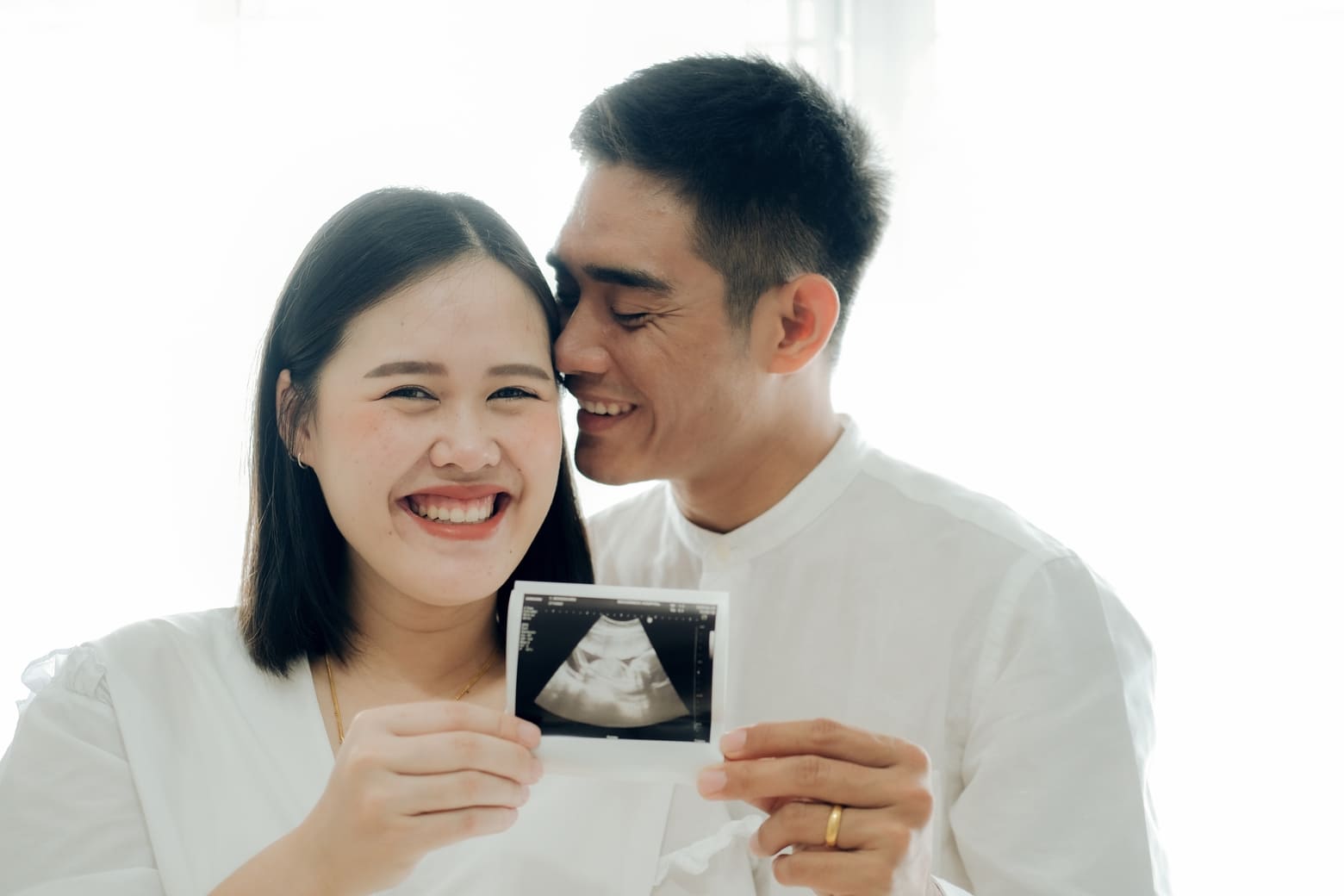 casal sorridente segurando imagem do ultrassom