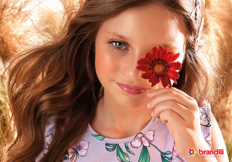 menina segurado uma flor no rosto
