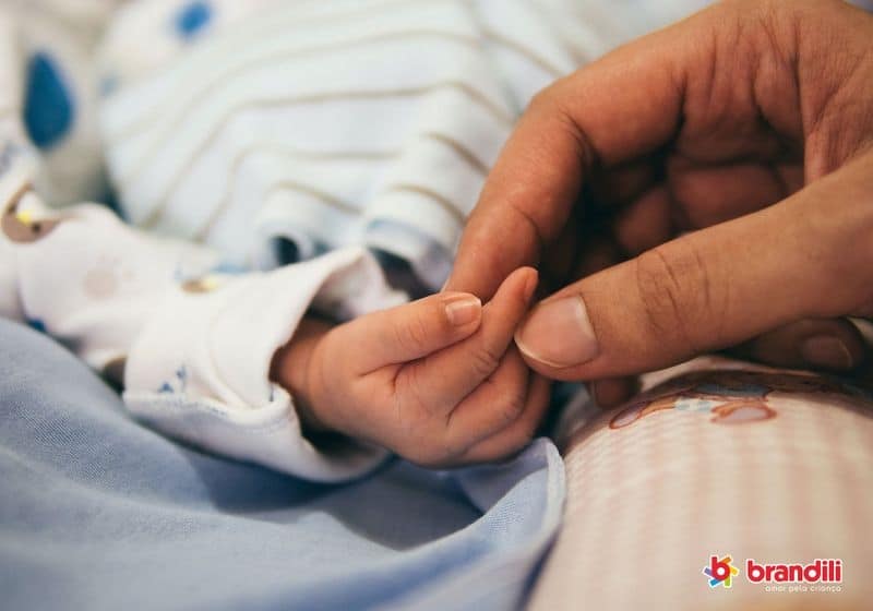 Mão segurando mãozinha de bebê recém-nascido
