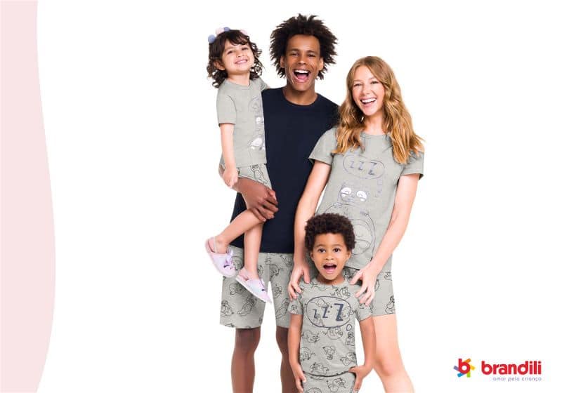casal de homem e mulher sorrindo com duas crianças usando pijama da mesma estampa 