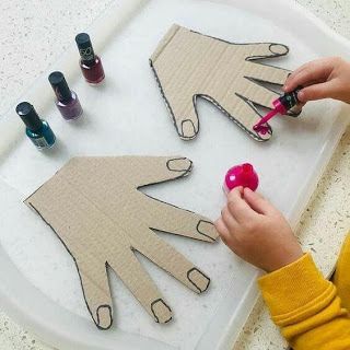Criança pintando recortes de papelão em formato de mãos