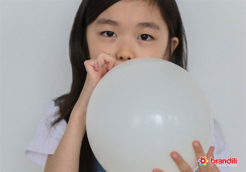 menina enchendo bexiga de balão branca 