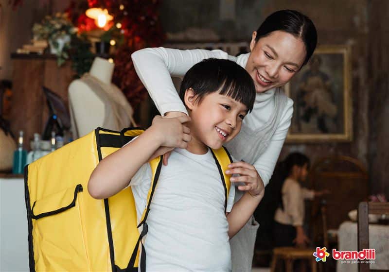 mulher e criança com mochila amarela indo para escola
