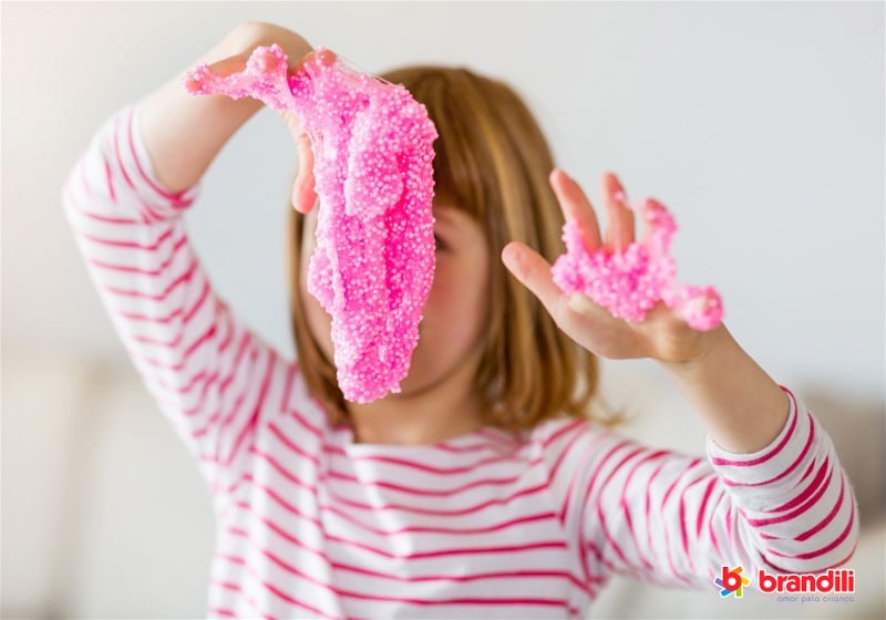 criança brincando com slime rosa