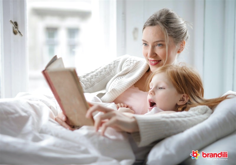 mãe lendo com filha na cama