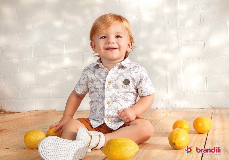 Foto de um bebê menino loiro sentado e sorrindo