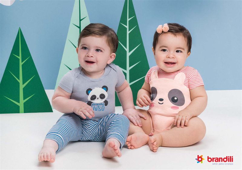 dois bebês sentado em cenário vestindo macacão de manga curta