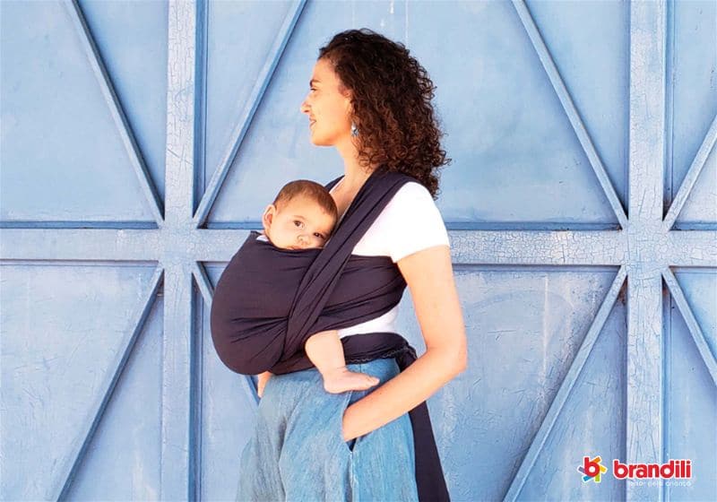 Mulher segura seu bebê com um Wrap Sling