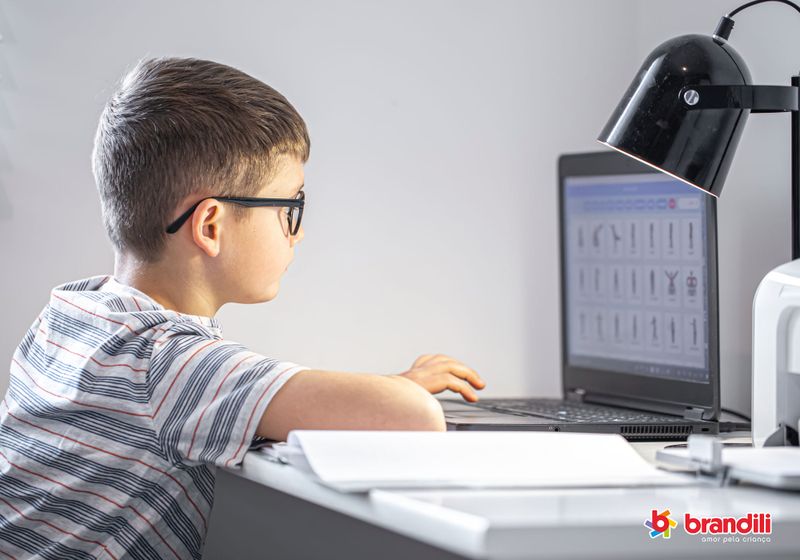 Menino usa óculos de grau enquanto estuda no computador