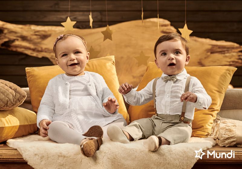 Bebês sentados sorrindo usando roupas brancas e fundo marrom