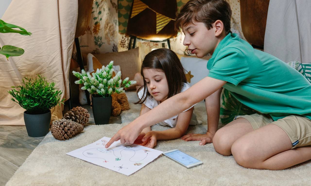 crianças com um mapa na mão bruincando de caça tesouro