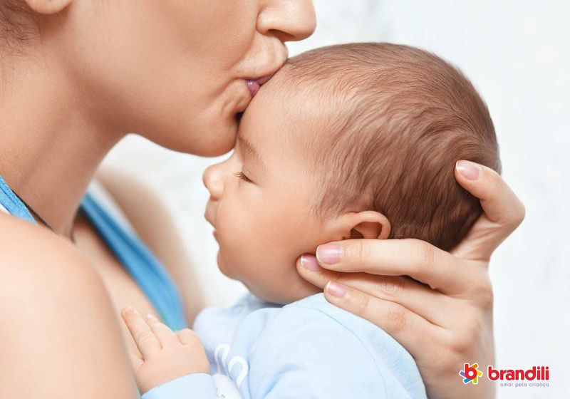 Mãe beija a testa de seu bebê com carinho