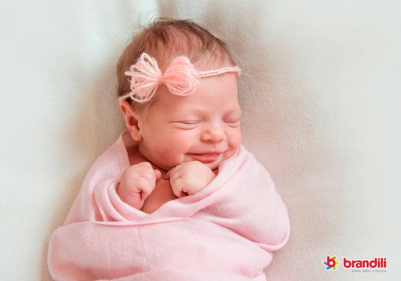 bebê enrolada em mantinha rosa sorri