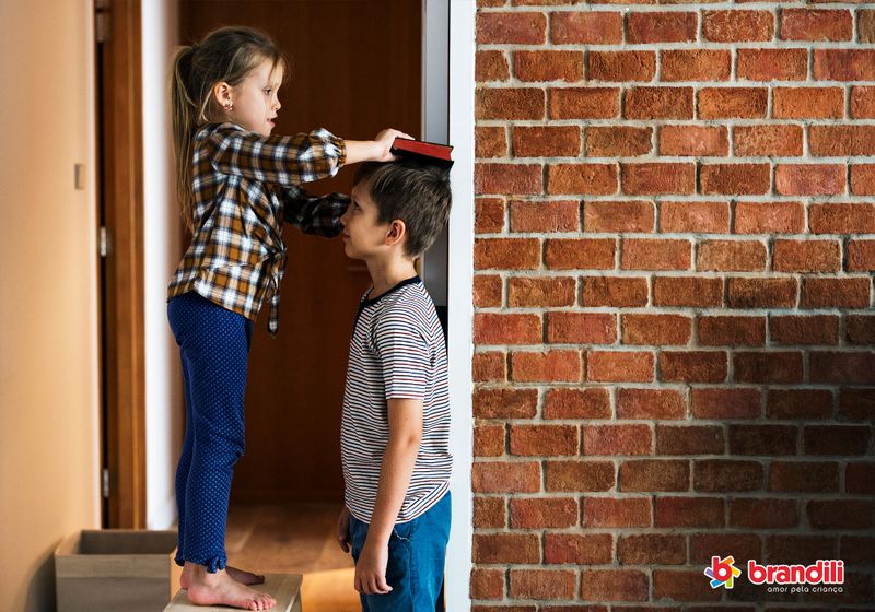 criança medindo a altura de outra criança na parede
