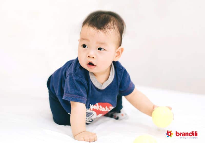 Bebê asiático brincando com bolinha