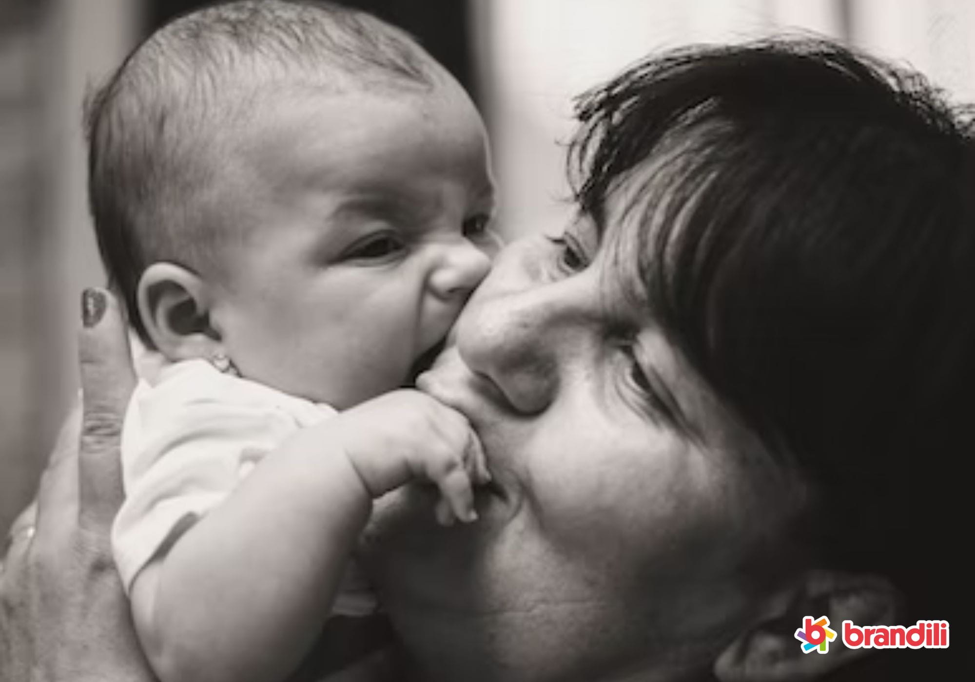 Fotografia preto e branco de mãe beijando seu filho pequeno com carinho