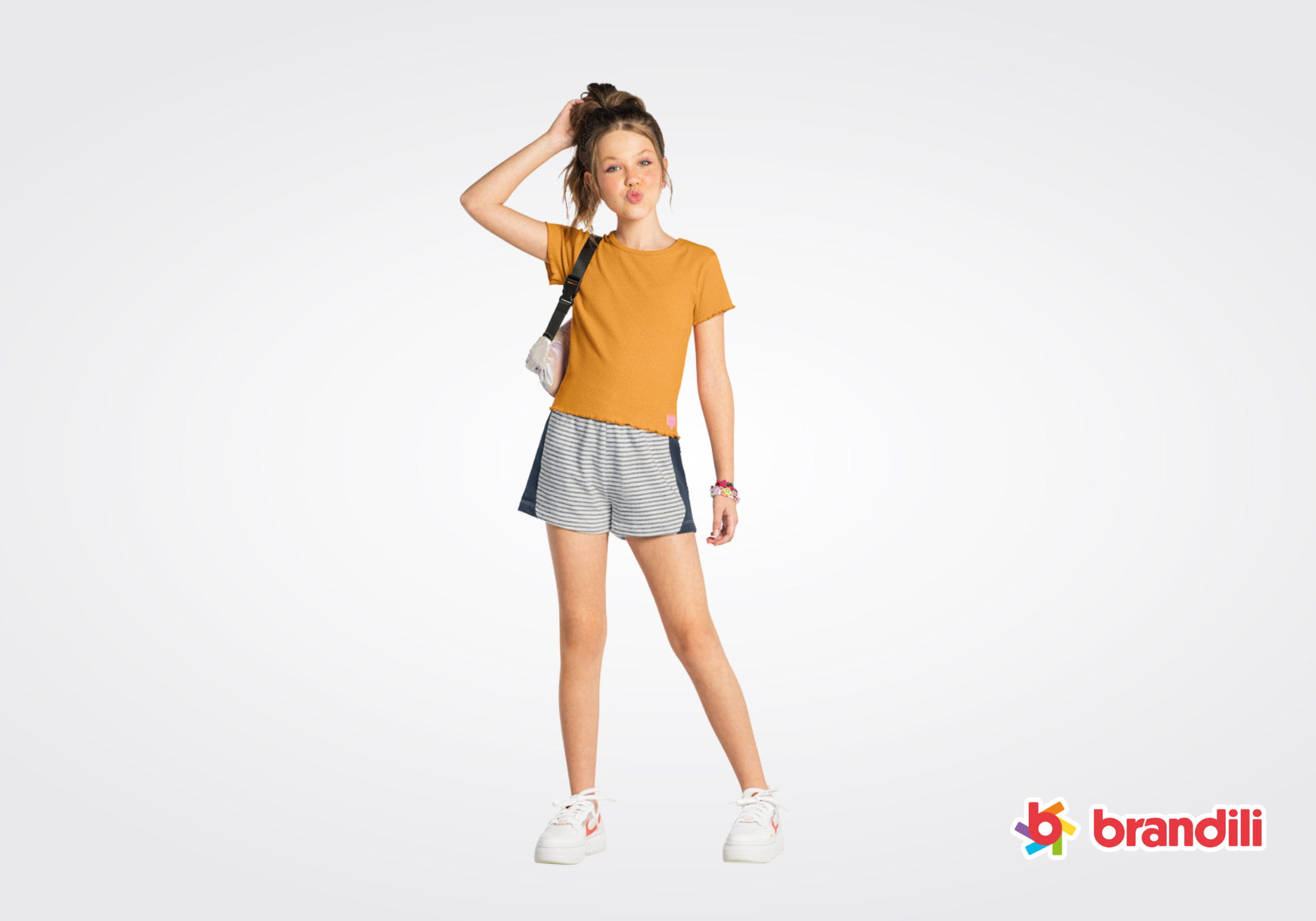 Menina jovem veste camiseta laranja e shorts listrado da Brandili