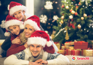 Pai, mãe e crianças com pijamas de Natal sorriem enquanto deitam em pilha