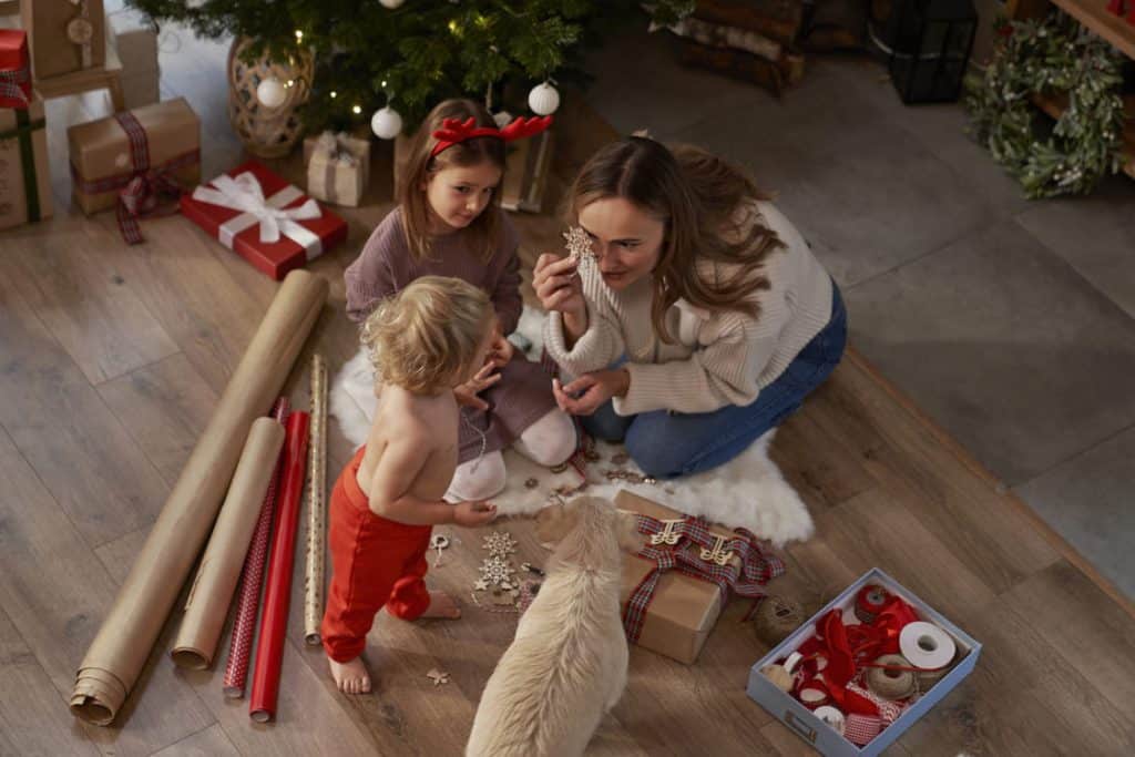 crianças abrindo o presente de natal embaixo da árvore de natal