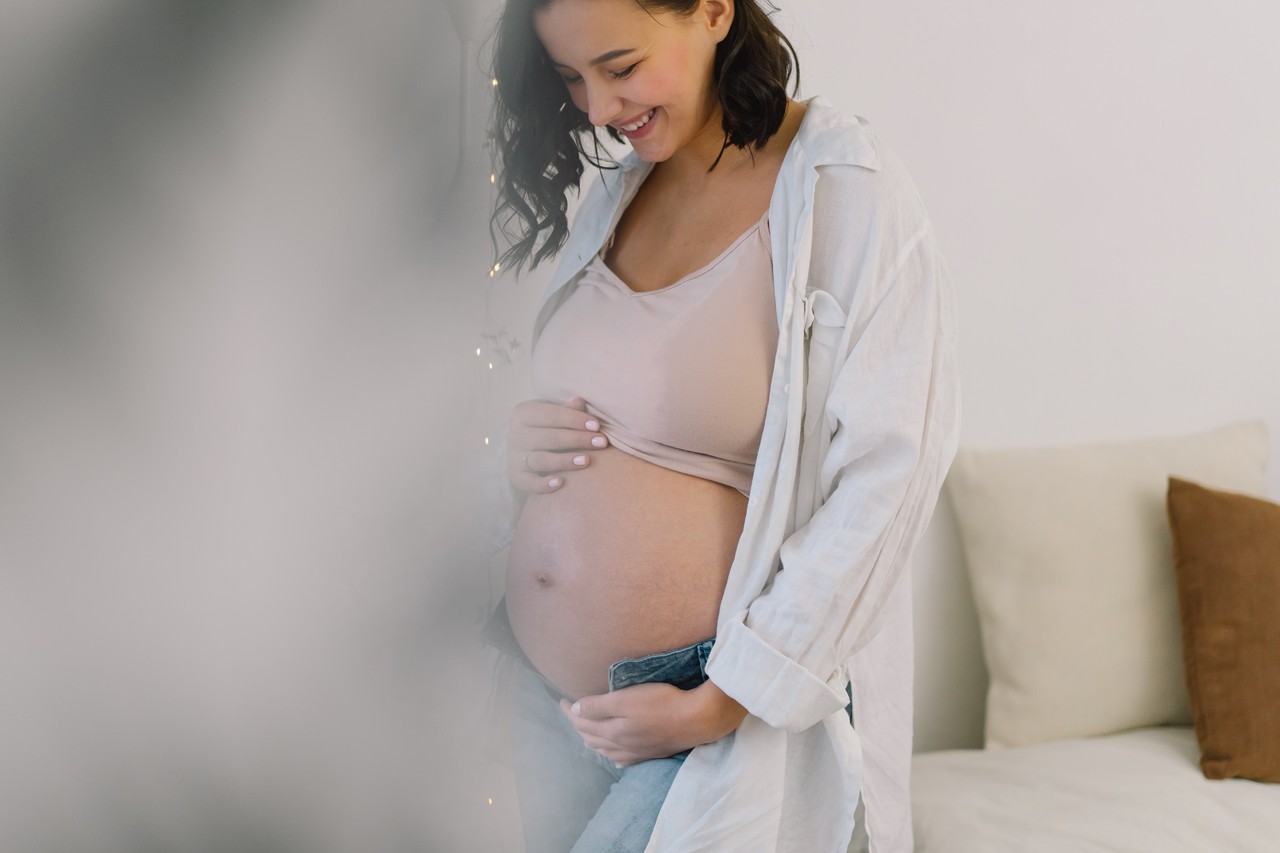 mulher grávida sorri ao sentir o bebê mexendo na barriga 
