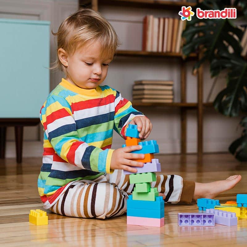 criança brinca com blocos de montar no chão de casa