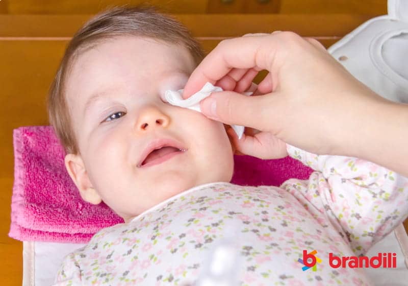 mãe limpando os olhos do bebê com gases 