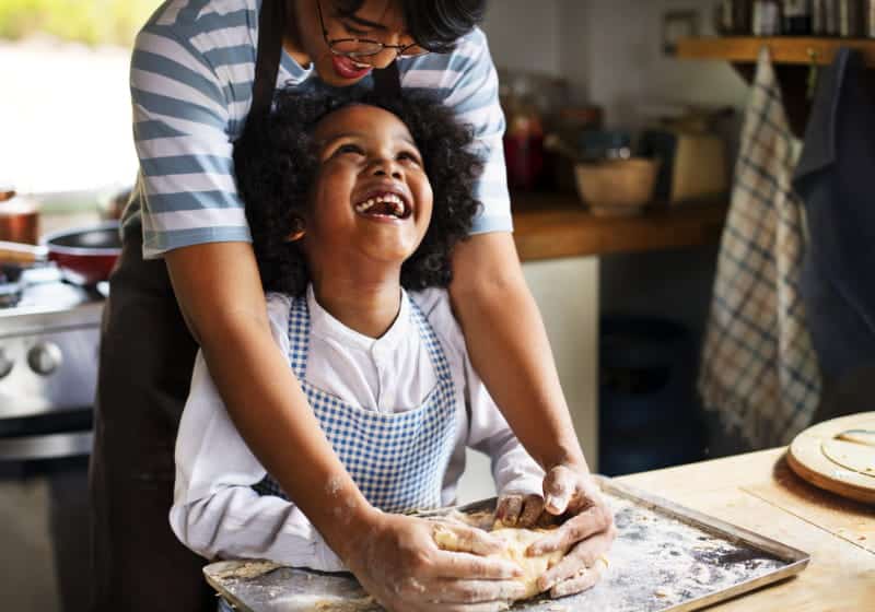 mãe e filho dando risada olhando um para outro na cozinha fazendo pão 