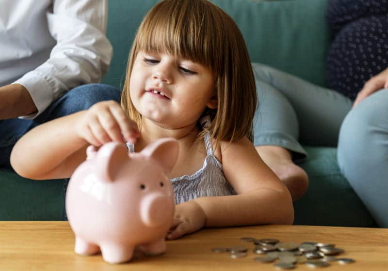 garotinha colocando moeda no cofrinho com os pais 