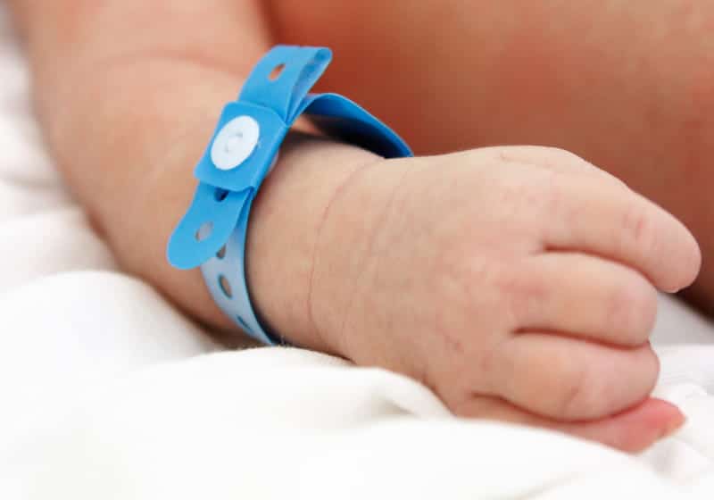 mãozinha de recém-nascidos com uma etiqueta azul no hospital maternidade