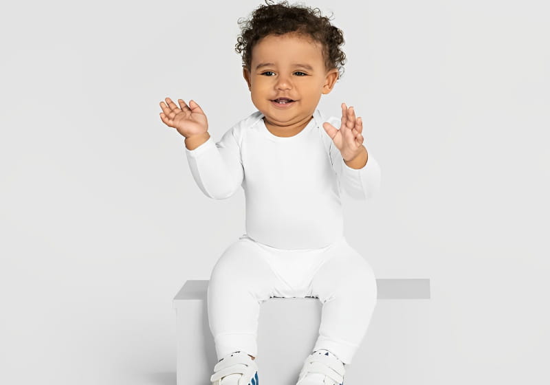 bebe sorridente sentado em uma plataforma branca no fundo branco 