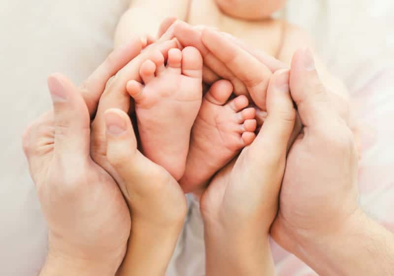 mãos de e mãe pai formando um coração no pé do bebê 
