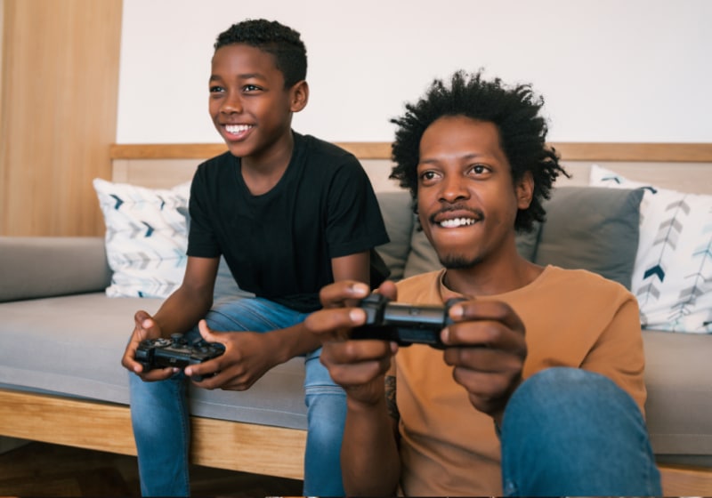 pai e filho jogando vídeo game na sala