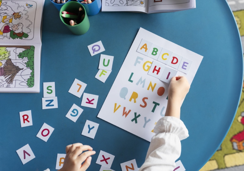 vista superior criança aprendendo as letras no jardim de infância