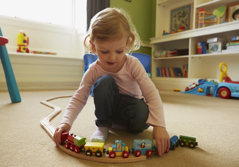 menininha brincando com trem de brinquedo na sala de brinquedos