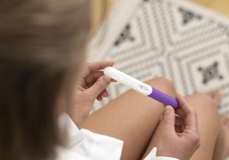 mulher segurando um teste de gravidez negativo