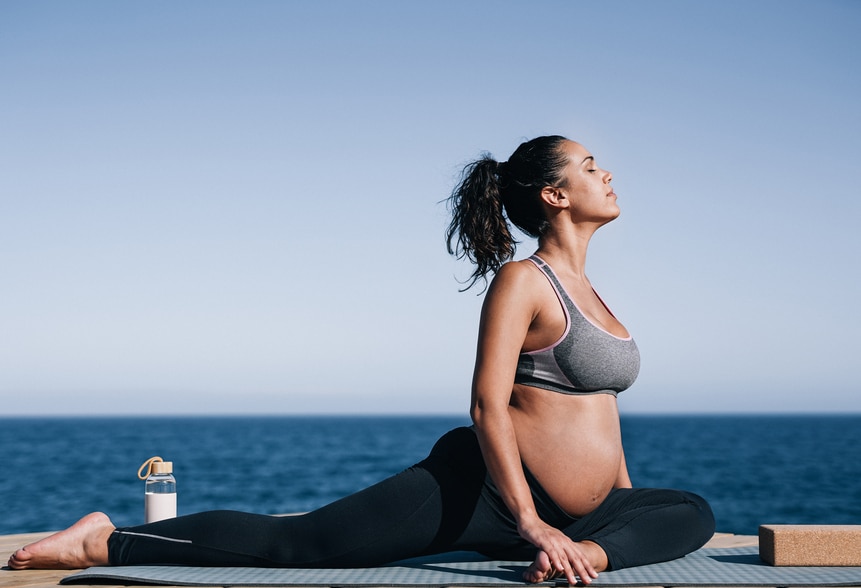 grávida fazendo ioga em frente ao mar para controlar a ansiedade