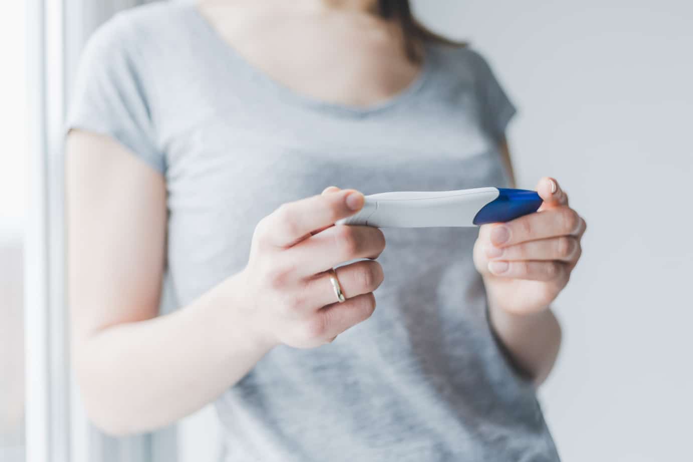mulher segurando um teste de gravidez na mão com o fundo desfocado
