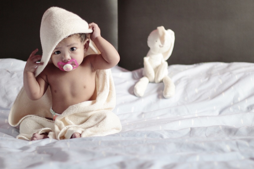 bebê enrolado em toalha sobre a cama