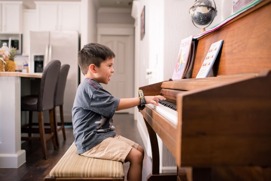 menino tocando piano na sala de jantar da casa