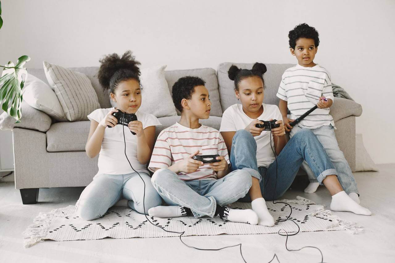 quatro crianças sentadas em uma sala jogando vídeo games
