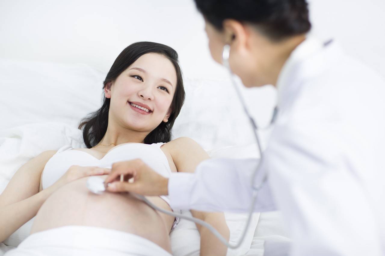  médico examinando mulher grávida em casa
