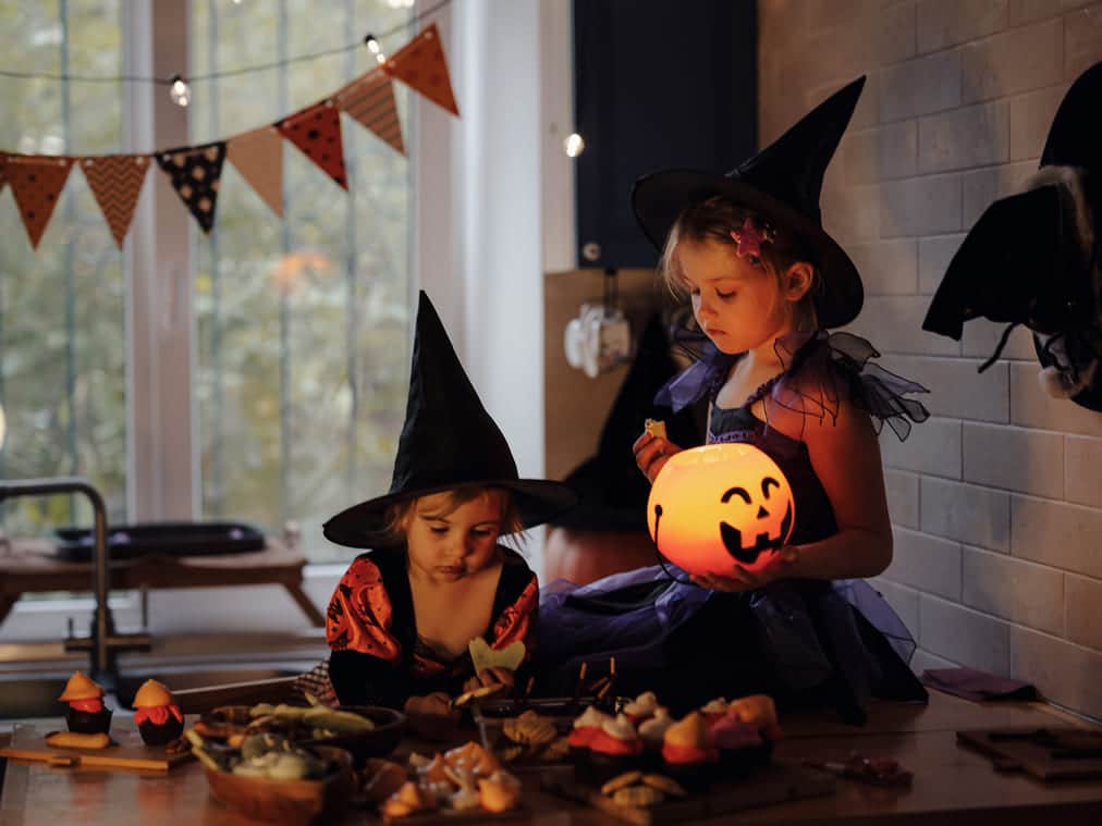 duas meninas brincando em uma sala decorada com bandeirinhas de hallowen